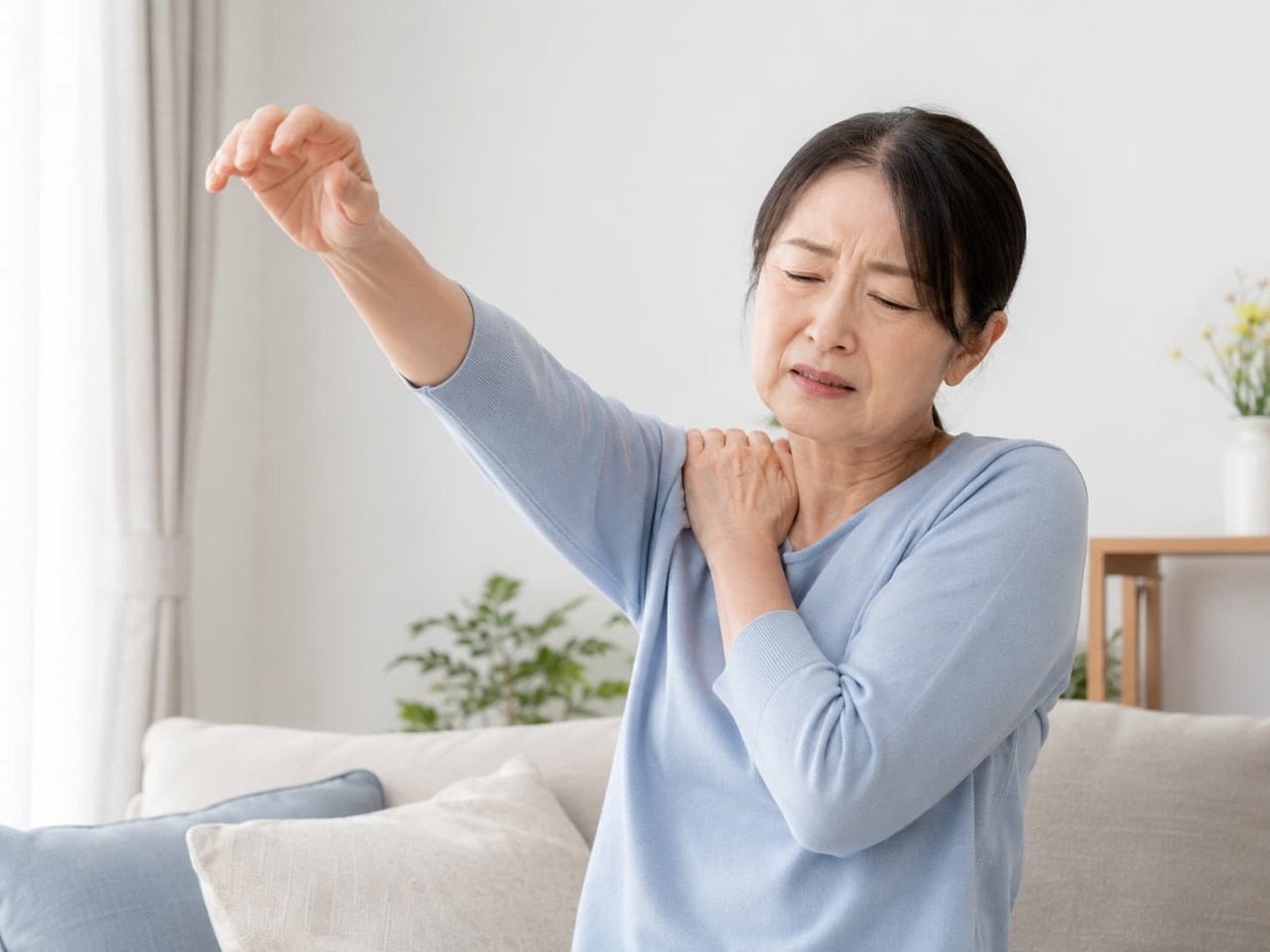 腕を上げようとして肩の痛みに困っている40〜60代の人物写真