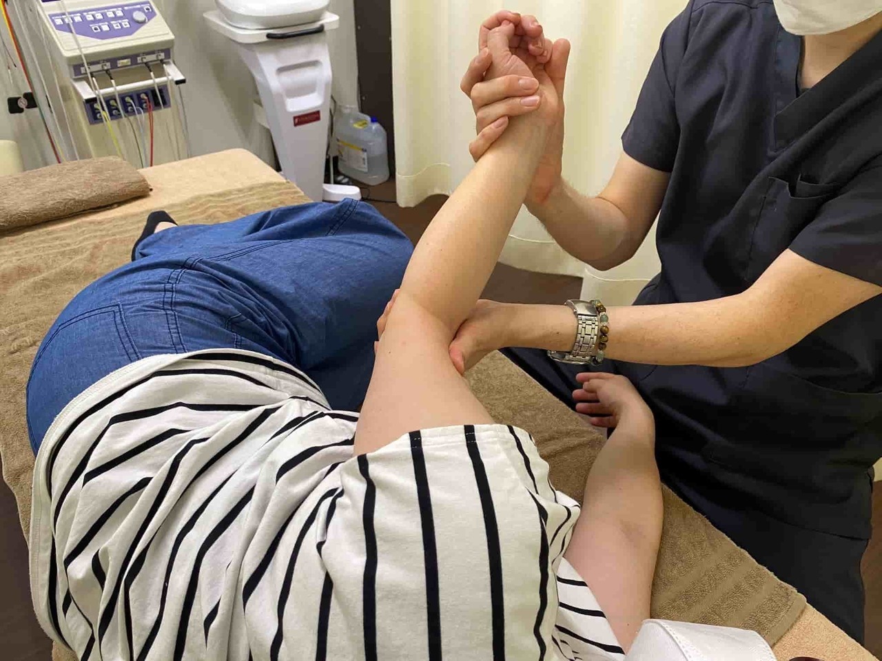 四十肩・五十肩の可動域を回復させるために、肩関節や肩甲骨の動きを確認しながら腕を調整している施術の様子。 関節包の滑りを取り戻すための関節モビライゼーション（SCJM法）の説明に対応した写真（姫路市の鍼灸整骨院一心堂）。