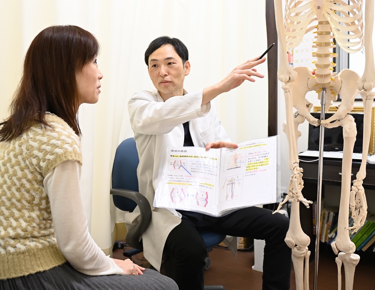 骨模型を使って症状説明を行う院長