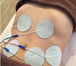 お腹にEMS電極パッドを装着して体幹を鍛える様子。姫路市の鍼灸整骨院一心堂では、JOYトレを用いて腰痛の再発予防や姿勢改善をサポートしています。