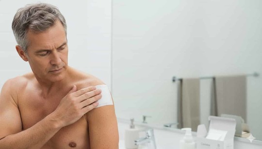 「肩の痛みを感じて湿布を貼る中年男性。四十肩・五十肩の急性期には痛みのコントロールが優先され、過度な運動を避けることが推奨される（姫路市・鍼灸整骨院一心堂）」