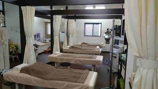 「鍼灸整骨院一心堂の院内風景。複数の施術ベッドが整然と配置された落ち着いた治療スペース。」