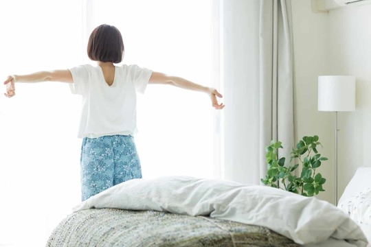 朝の光の中で気持ちよく背伸びをする女性。姫路市の鍼灸整骨院一心堂では、腰痛改善後も再発予防や体のメンテナンスをサポートしています。