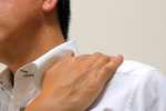 肩こりを訴える男性のイメージ写真（首に手を当てる様子）